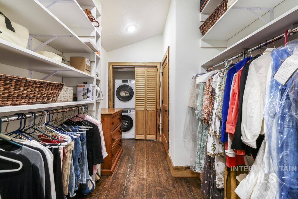 65 Goat Creek Way Stanley, ID 83278 - Photo 24 of 32 Walk-in closet featuring wood-finish flooring, white built-in shelving, two clothing rods for hanging storage, and a built-in stacked washer and dryer unit