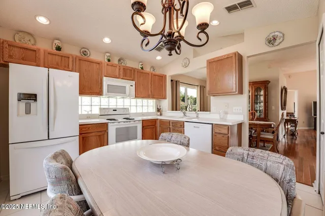 a kitchen with stainless steel appliances kitchen island granite countertop a refrigerator a oven a sink a dining table and chairs with wooden floor