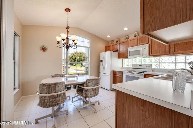 a room with stainless steel appliances kitchen island granite countertop furniture and a chandelier