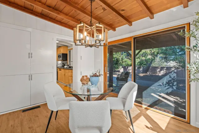 a dining room with wooden floor a chandelier a glass table and chairs