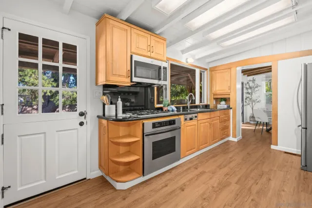 a kitchen with stainless steel appliances kitchen island granite countertop a stove a refrigerator a sink and dishwasher with wooden floor