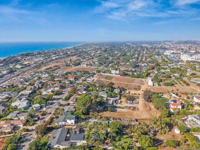 an aerial view of ocean and residential houses with outdoor space