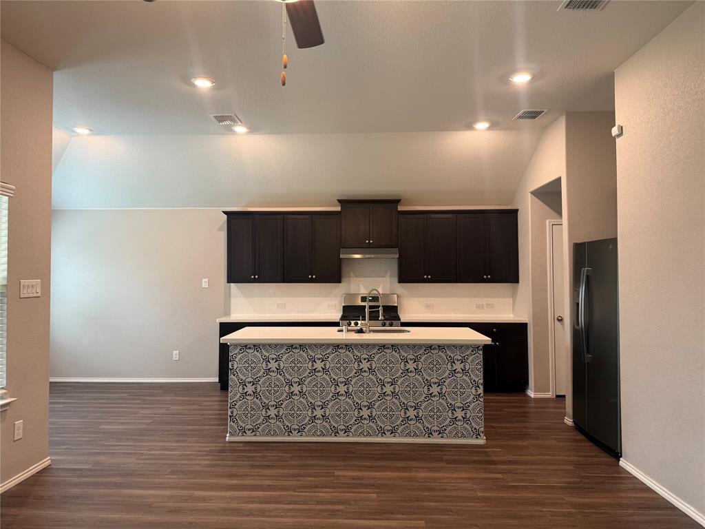 1004 Rising Moon Drive Fort Worth, TX 76052 - Photo 5 of 13 Open-concept kitchen featuring an island with decorative tile, dark wood cabinetry, stainless steel appliances, and wood-finish flooring