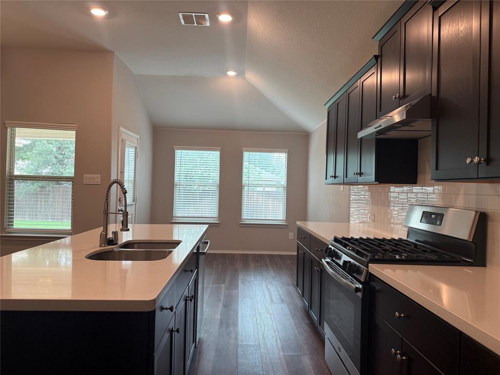 1004 Rising Moon Drive Fort Worth, TX 76052 - Photo 6 of 13 Modern kitchen featuring dark wood-finish cabinetry, light countertops, and a stainless steel range with matching range hood