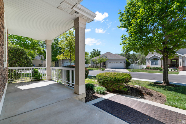 1417 Blacksmith Lane Draper, UT 84020 - Photo 46 of 57 Covered concrete porch with white railing, stone facade, and mature landscaping
