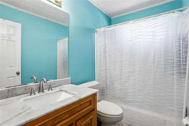 a bathroom with a granite countertop toilet a sink a mirror and shower curtain
