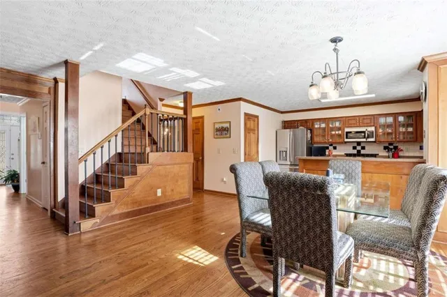 a view of a livingroom with furniture stairs wooden floor and windows