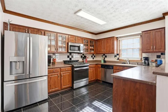 a kitchen with stainless steel appliances granite countertop a refrigerator stove microwave and sink