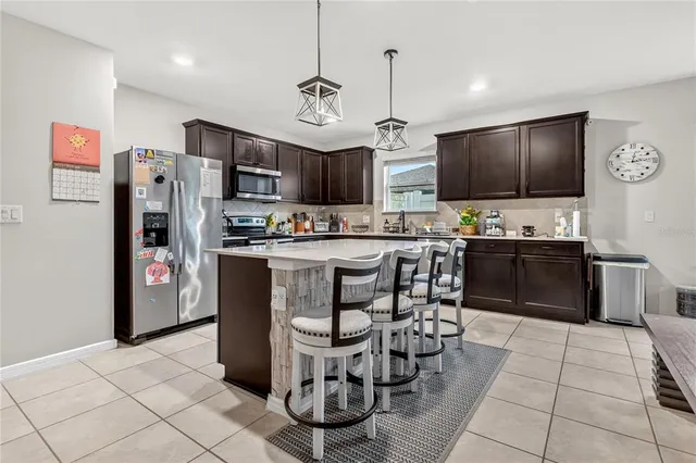 a kitchen with stainless steel appliances a refrigerator a stove a sink a dining table and chairs