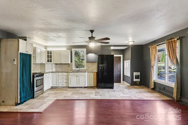 a kitchen with stainless steel appliances kitchen island granite countertop a refrigerator a stove a sink and a large window