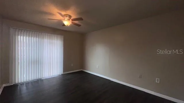 an empty room with wooden floor fan and windows