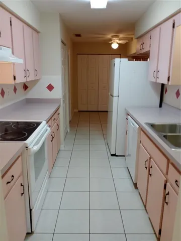 a utility room with stainless steel appliances wooden floor sink and cabinets