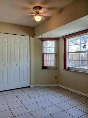 an empty room with a chandelier fan and windows