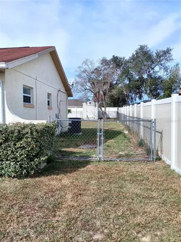 a view of backyard of house with wooden fence
