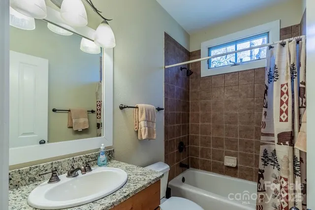 a bathroom with a granite countertop sink a mirror a bathtub and shower