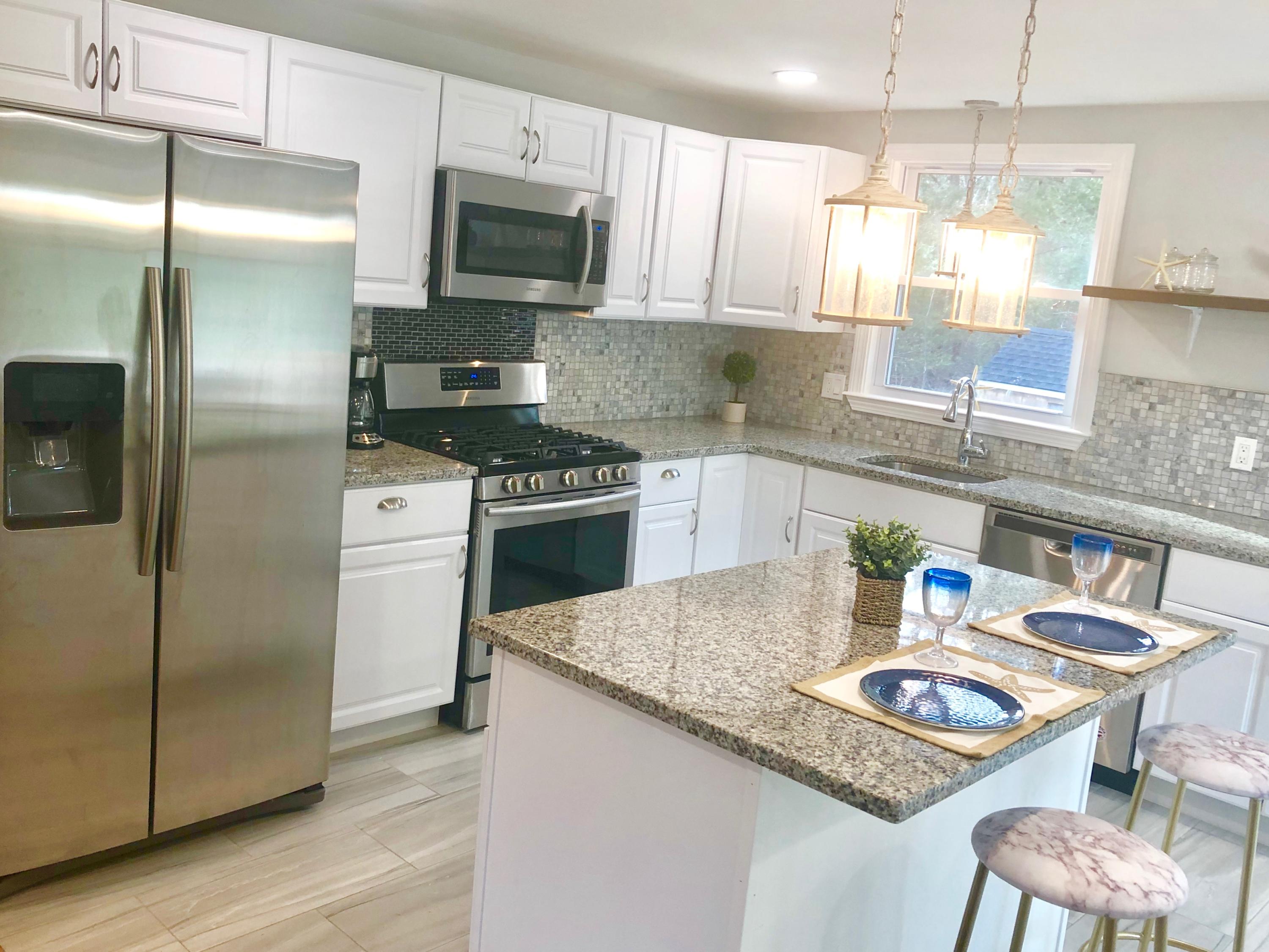 57 Stage Coach Road Centerville, MA 02632 - Photo 5 of 34 a kitchen with granite countertop kitchen island stainless steel appliances a sink a stove a refrigerator cabinets and dining table