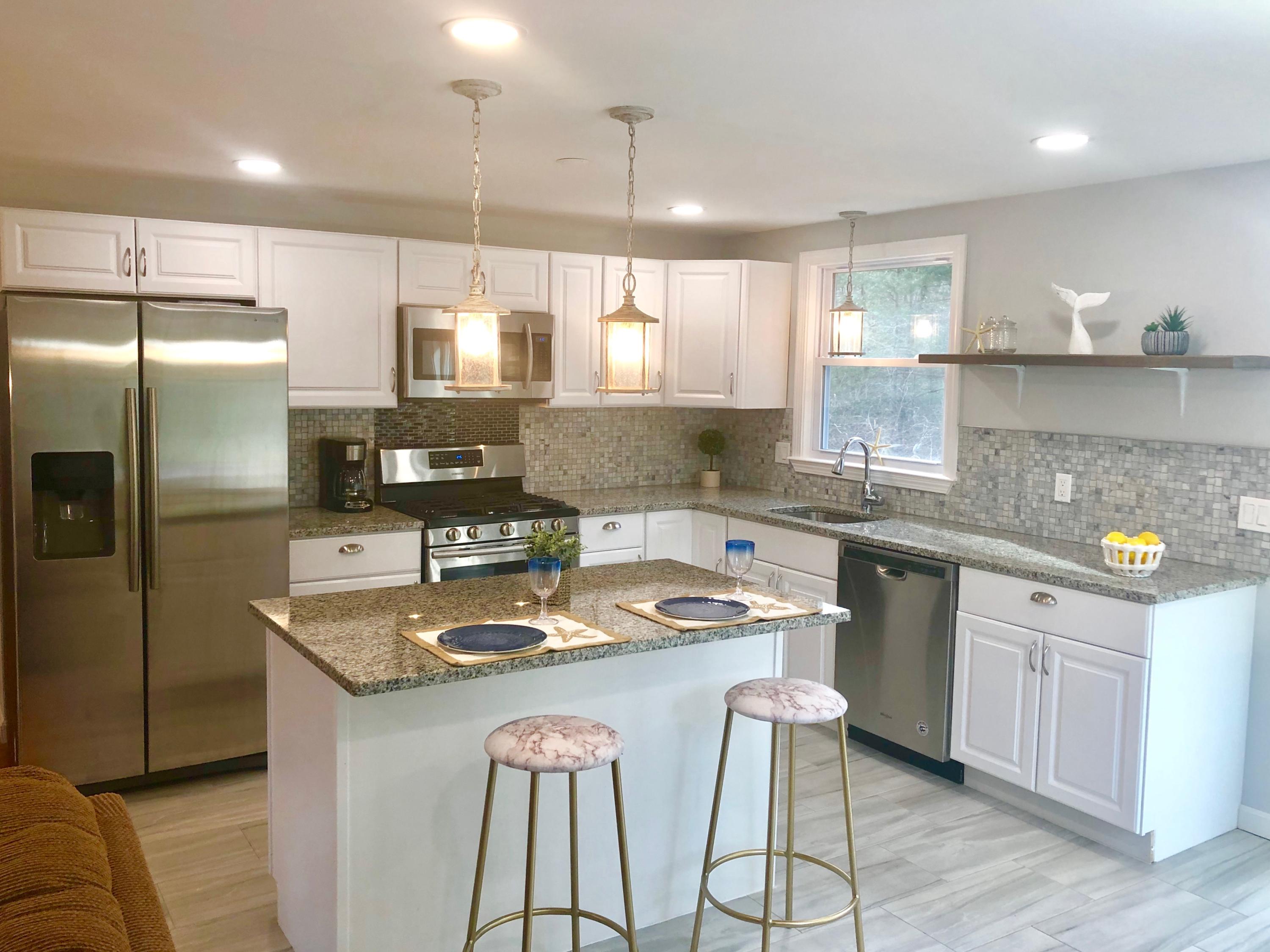 57 Stage Coach Road Centerville, MA 02632 - Photo 10 of 34 a kitchen with stainless steel appliances granite countertop a sink a stove a refrigerator cabinets and chairs