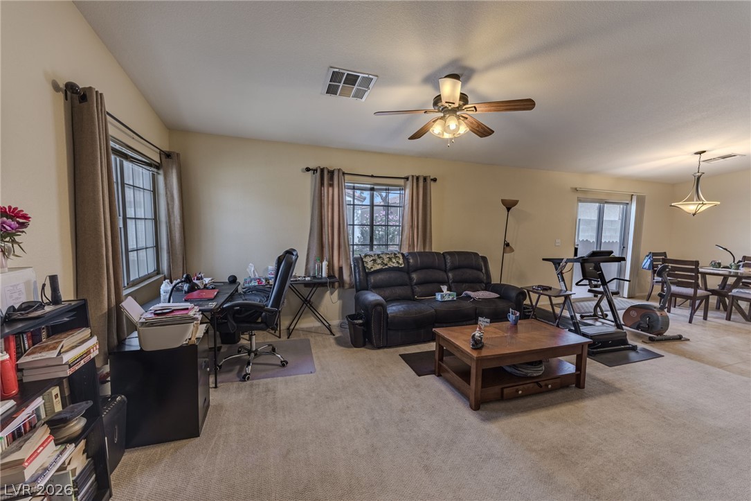 4994 Mascaro Drive Las Vegas, NV 89122 - Photo 2 of 30 A versatile living area with neutral carpet flooring and a ceiling fan for comfort.
