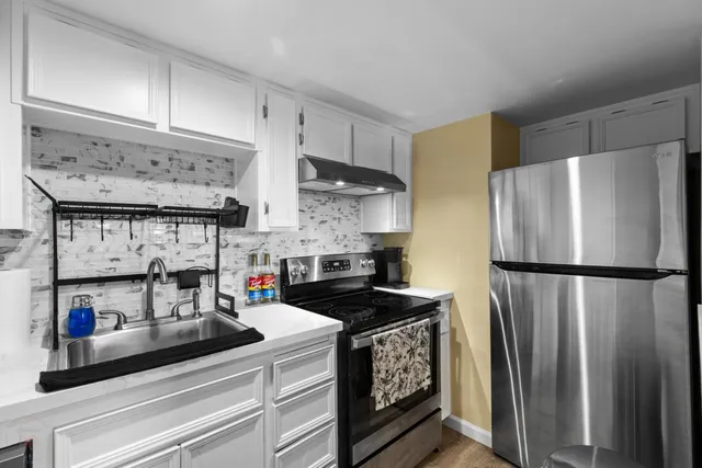 a kitchen with stainless steel appliances a refrigerator a sink and cabinets