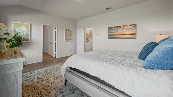 a spacious bedroom with a bed and a potted plant