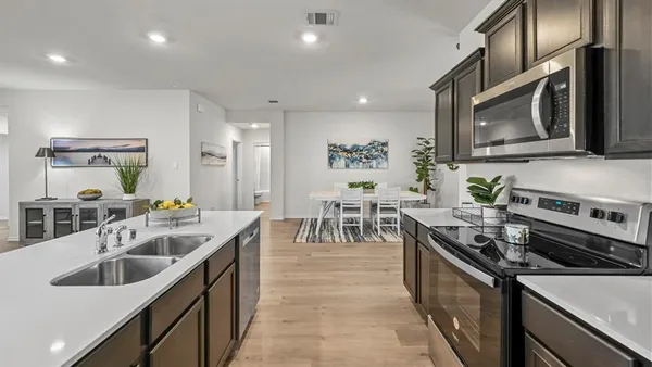 a kitchen with stainless steel appliances a dining table chairs refrigerator and microwave