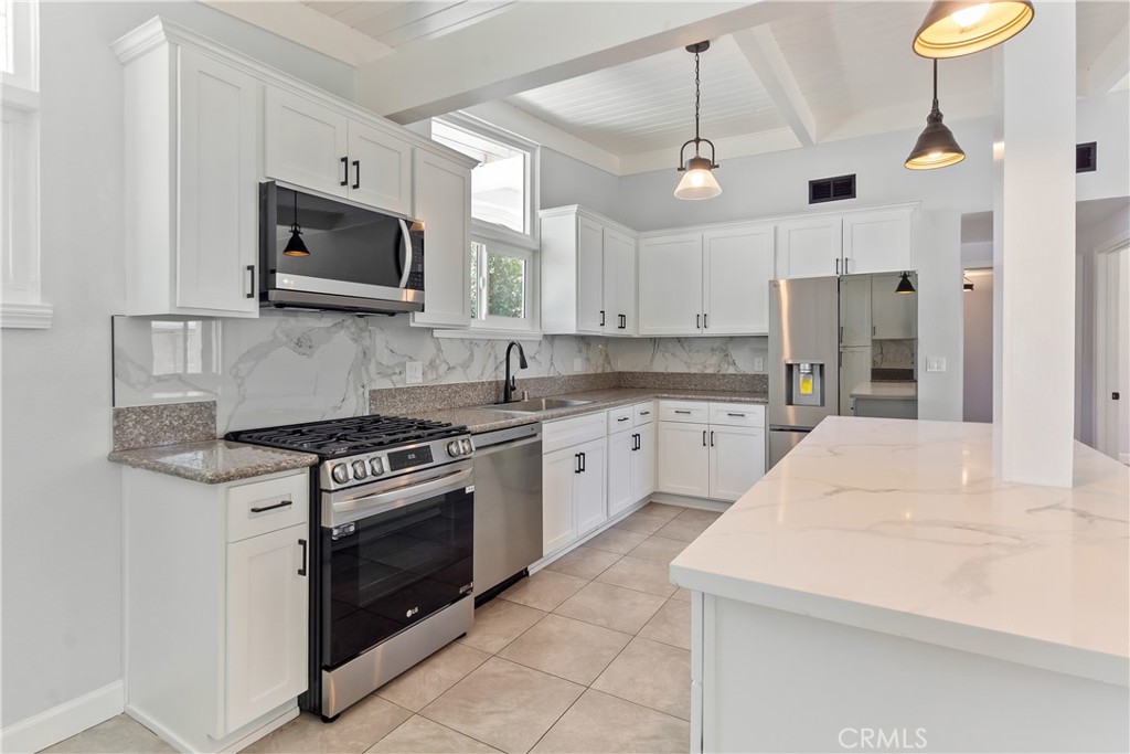 38995 Juniper Tree Road Palmdale, CA 93551 - Photo 10 of 22 a kitchen with stainless steel appliances a stove a microwave and white cabinets