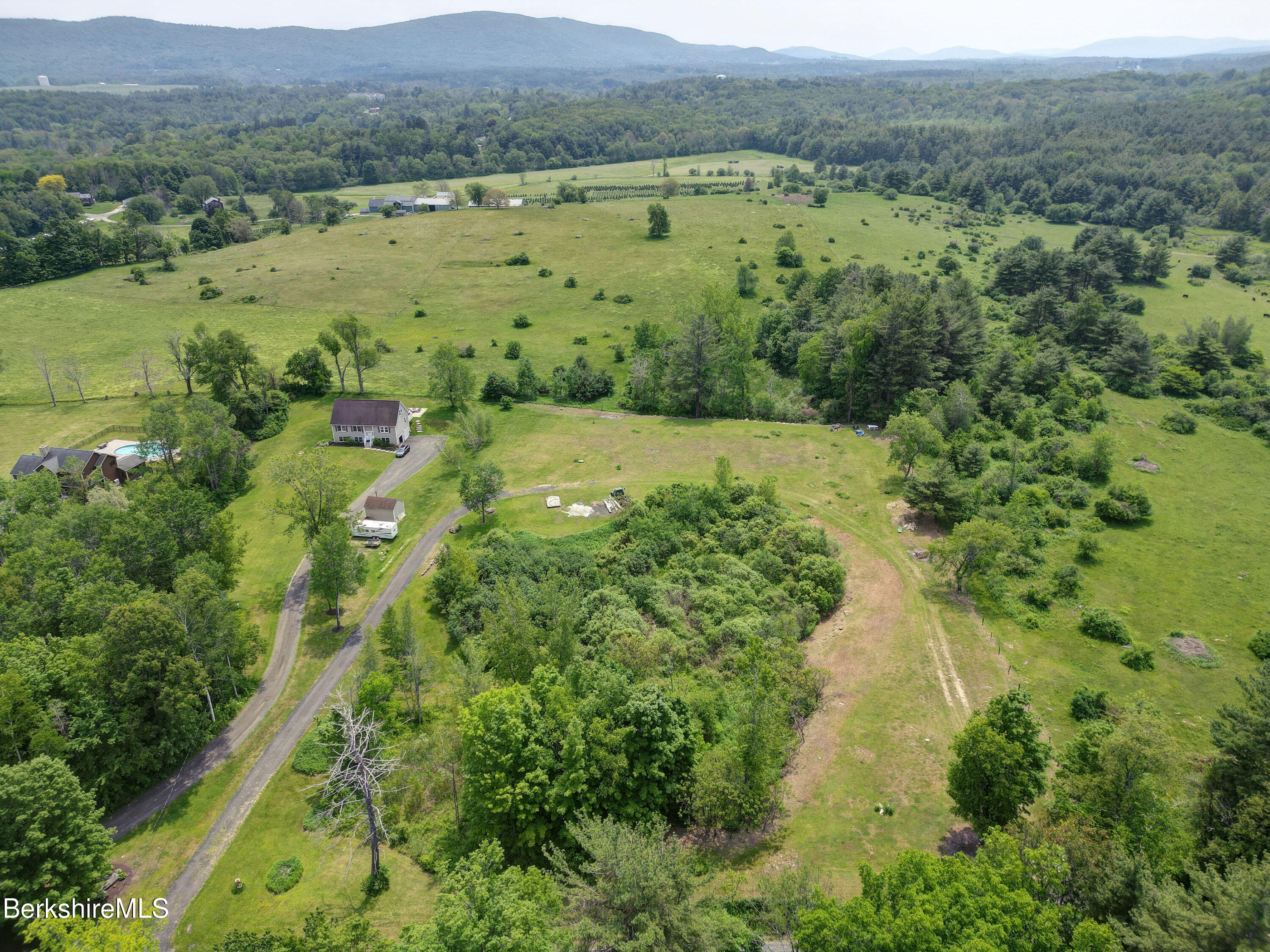 an aerial view of green landscape with trees houses and mountain view