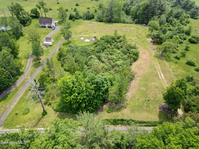 an aerial view of residential houses with outdoor space and trees all around
