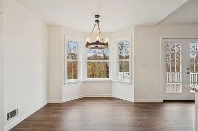an empty room with wooden floor chandelier and windows