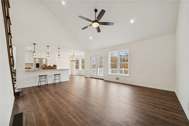 a view of an empty room with wooden floor and a ceiling fan