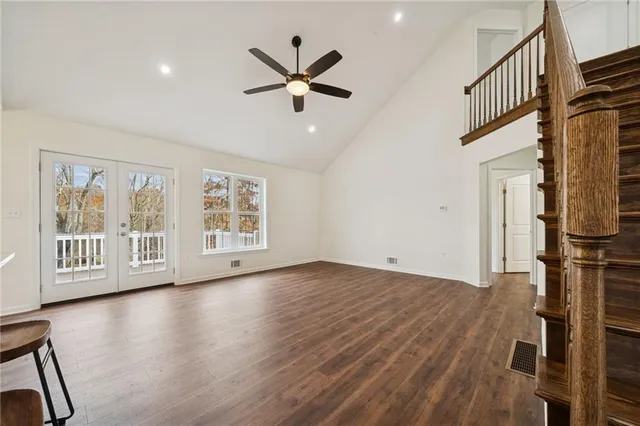 a view of an empty room with wooden floor and a ceiling fan