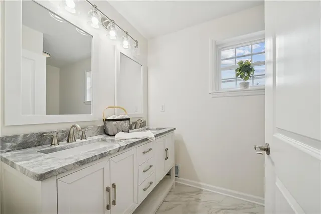 a bathroom with a granite countertop sink a large mirror a and a window