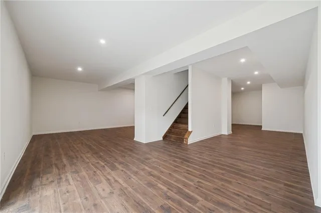 a view of an empty room with wooden floor and stairs