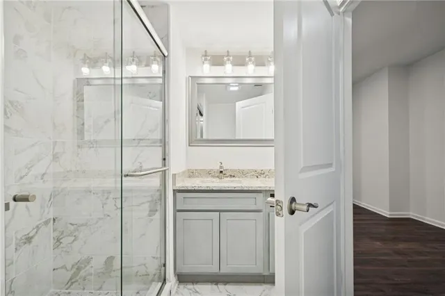 a bathroom with a granite countertop sink a mirror and shower