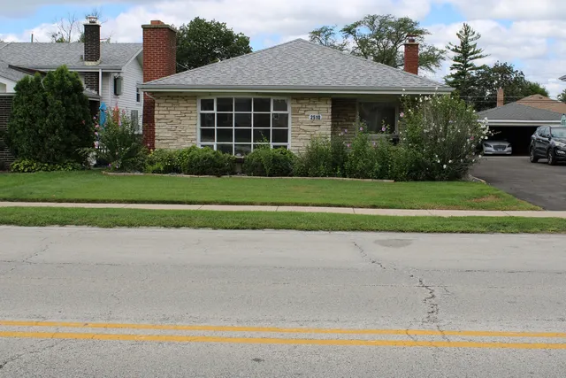 a front view of a house with a yard and potted plants