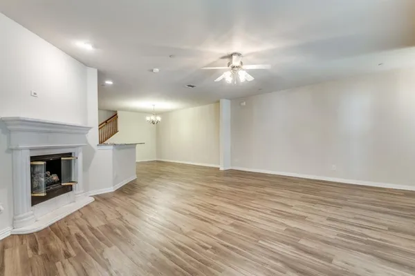 an empty room with wooden floor fireplace and chandelier