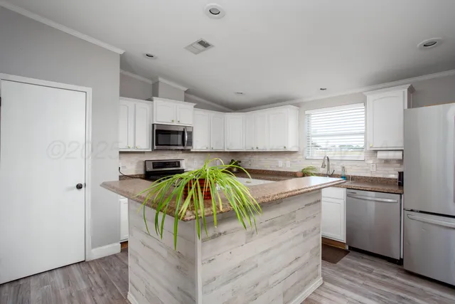 a kitchen with stainless steel appliances granite countertop a refrigerator a stove top oven a sink and dishwasher with wooden floor