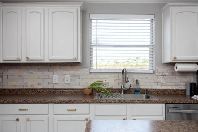 a kitchen with granite countertop white cabinets and window