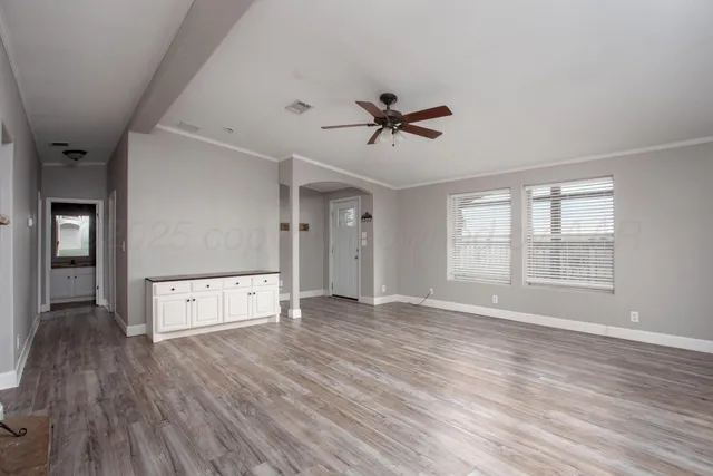 a view of an empty room with window and wooden floor