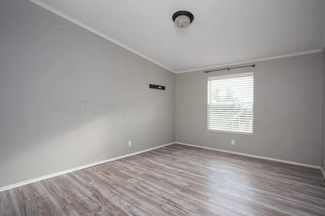 a view of a kitchen and an empty room with wooden floor