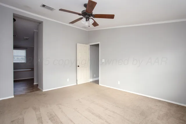 a view of an empty room with wooden floor and a ceiling fan
