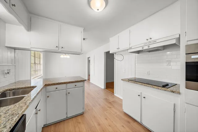 a kitchen with granite countertop a sink cabinets and stainless steel appliances