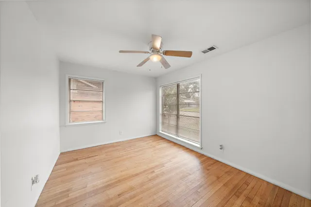 a view of empty room with wooden floor and fan