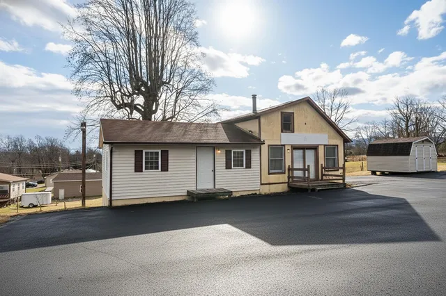 a view of a white house with a large tree