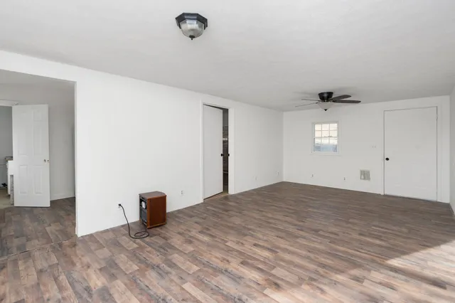 a view of an empty room with wooden floor and windows