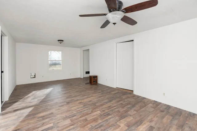 an empty room with windows and fan
