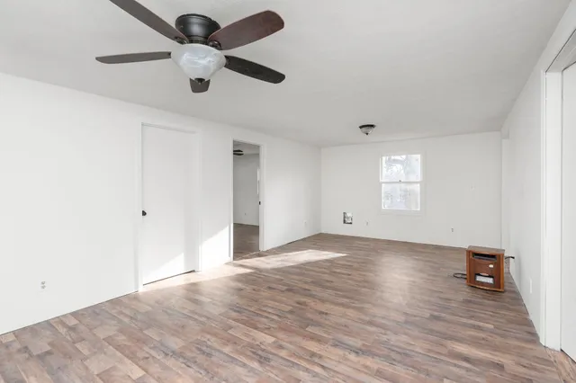 a view of an empty room with a window and wooden floor