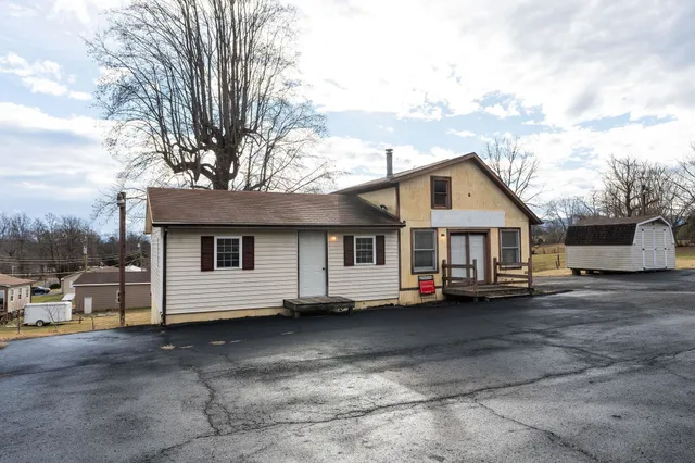 a view of a white house with a large space and a road