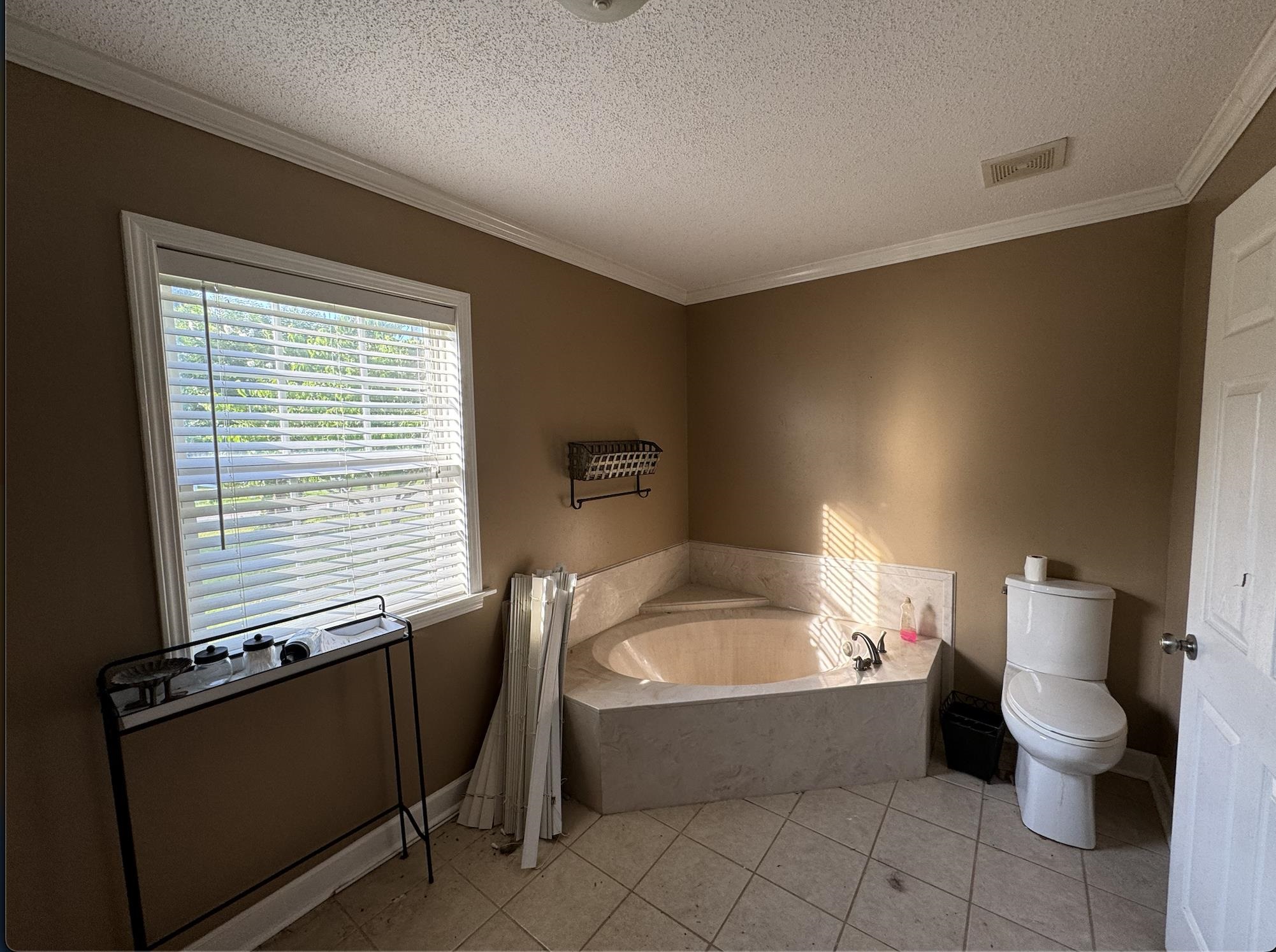 1336 Dunlap Orphanage Road Brighton, TN 38011 - Photo 14 of 14 Bathroom featuring a relaxing tiled bath, toilet, tile floors, crown molding, and a textured ceiling