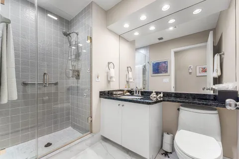 a bathroom with a granite countertop sink mirror and toilet